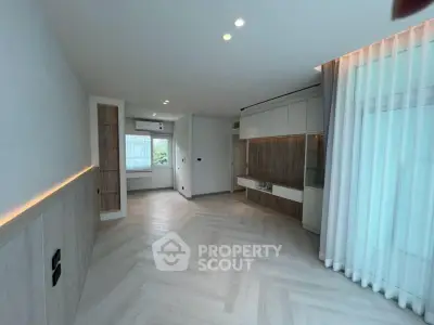 Spacious modern living room with elegant wood flooring and stylish built-in storage.