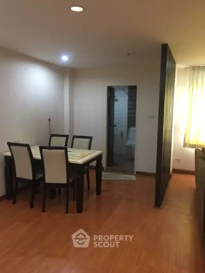 Cozy dining area with wooden flooring and modern furniture in a well-lit apartment