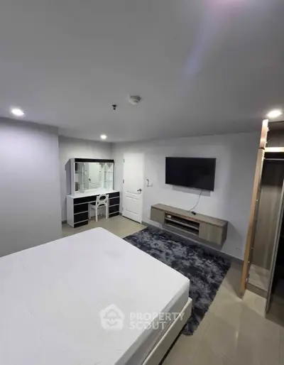 Modern bedroom with sleek furniture and wall-mounted TV in a stylish apartment.