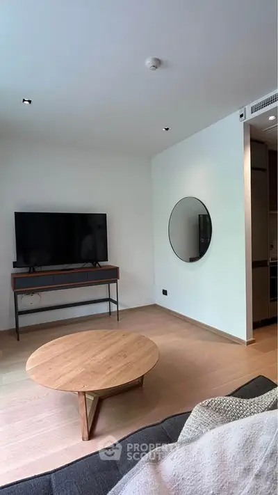 Modern living room with sleek TV setup and stylish round mirror