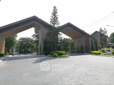 Modern gated entrance with lush landscaping and contemporary design.