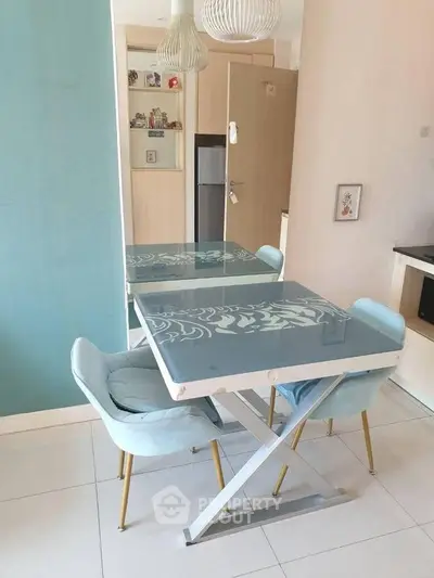 Modern dining area with stylish glass table and pastel chairs in a cozy apartment setting.
