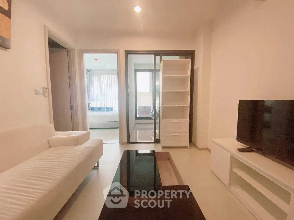 Modern living room with sleek furniture and open layout, featuring a cozy sofa and flat-screen TV.