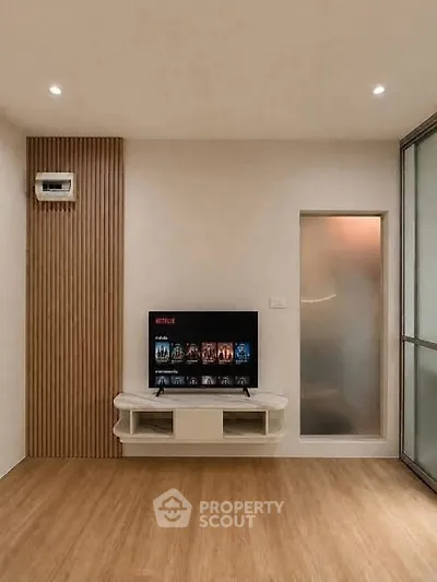 Modern living room with wall-mounted TV and sleek wooden flooring