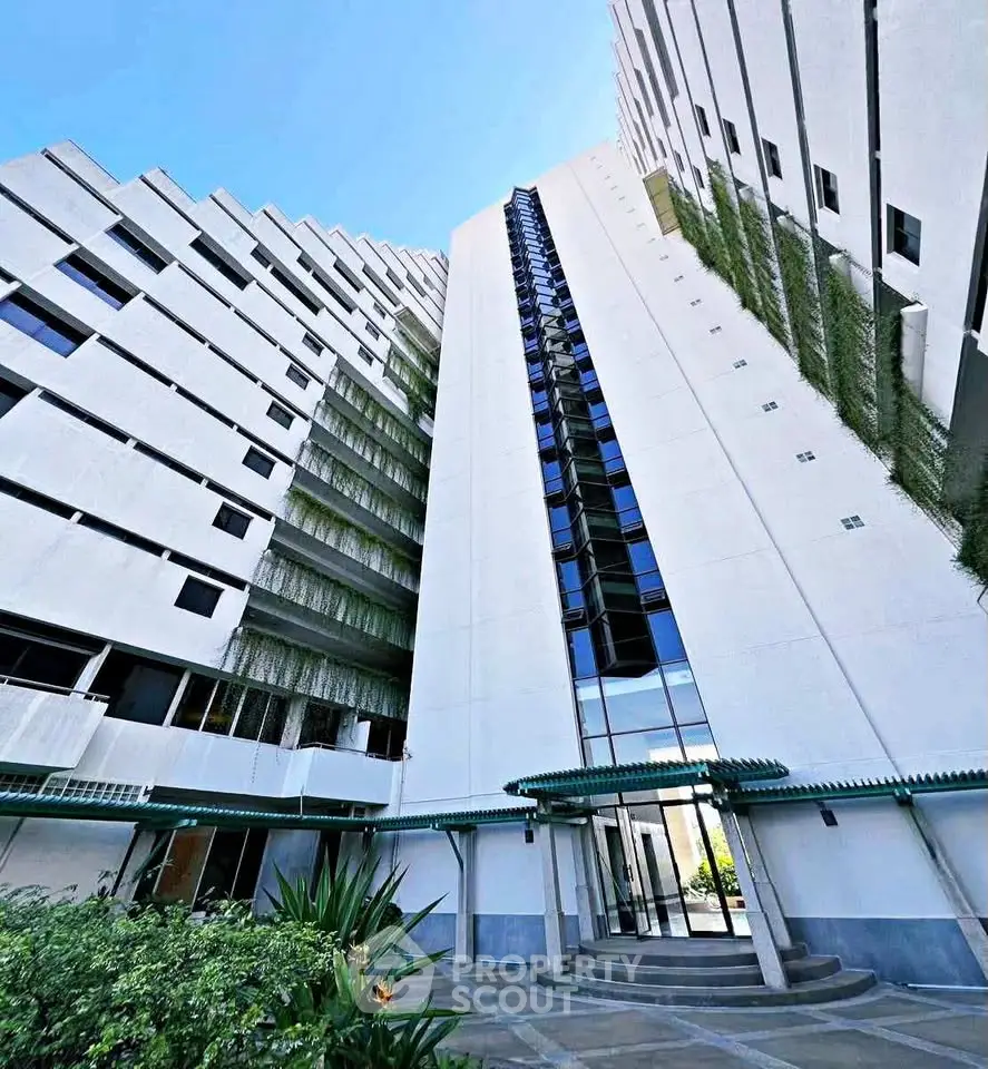 Modern high-rise building with unique architectural design and lush greenery