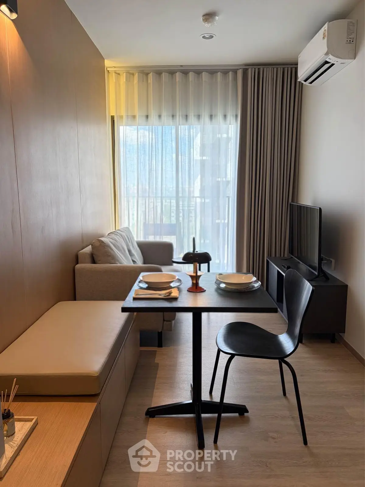 Modern living room with dining area, featuring sleek furniture and natural light from large windows.