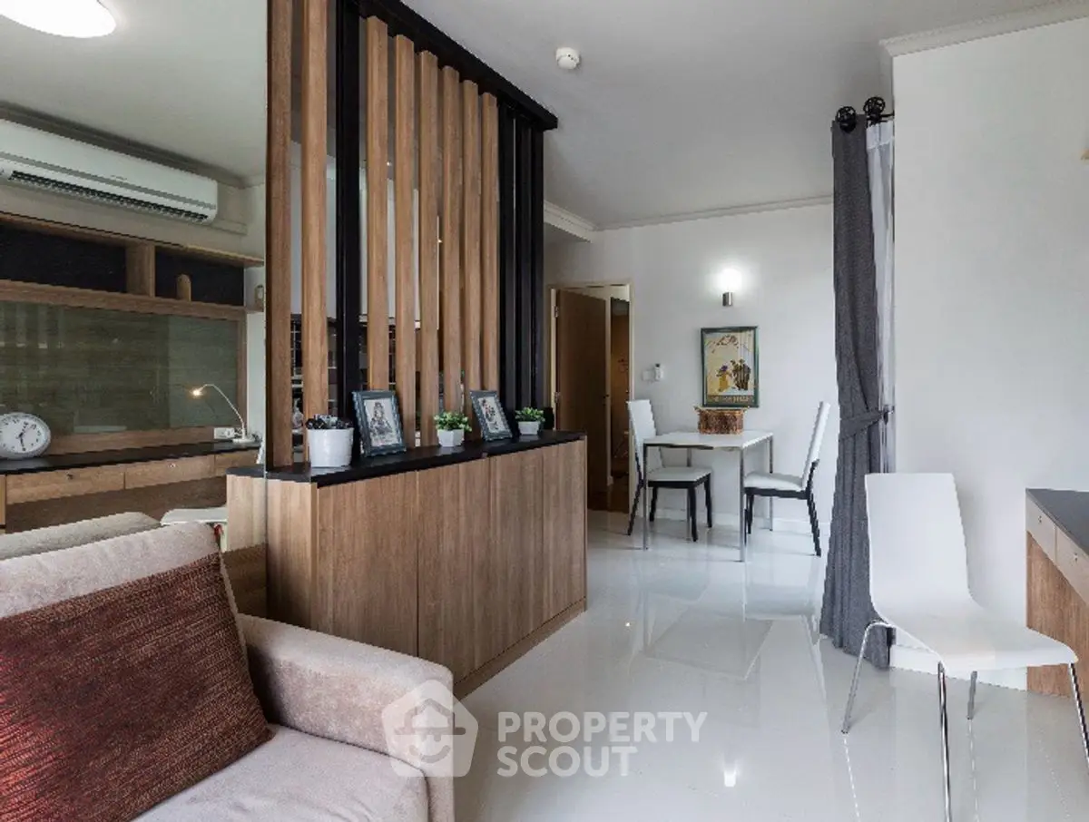 Modern living room with stylish partition and dining area, featuring sleek furniture and bright ambiance.