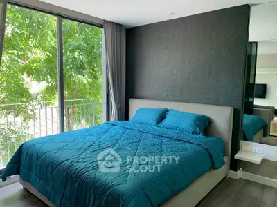 Modern bedroom with large window and stylish decor, offering a serene view of lush greenery.