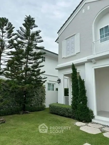 Charming white house exterior with lush garden and elegant architectural details.