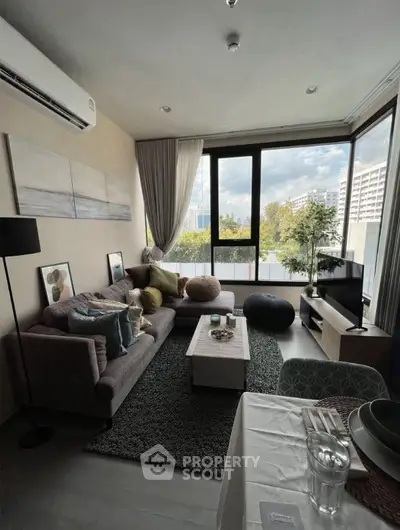 Modern living room with large windows and stylish decor in a high-rise apartment.