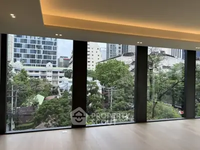 Spacious room with floor-to-ceiling windows offering a stunning cityscape view.