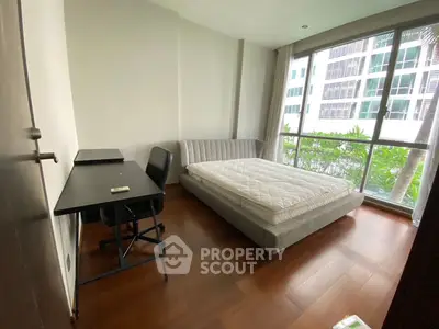 Modern bedroom with large window and hardwood floors in urban apartment