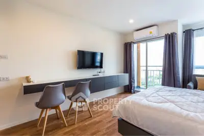 Modern bedroom with balcony, featuring sleek furniture and a wall-mounted TV, perfect for urban living.