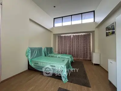 Spacious bedroom with high ceiling and large windows for natural light.