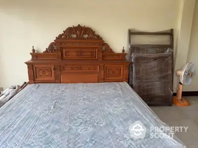 Spacious bedroom with ornate wooden bed and fan, ideal for comfort and style.