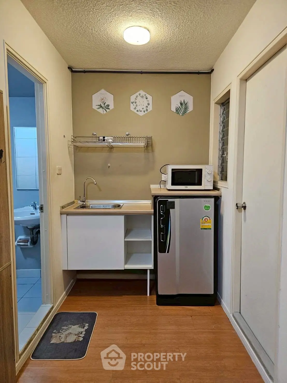 Compact kitchen with modern appliances and adjacent bathroom view