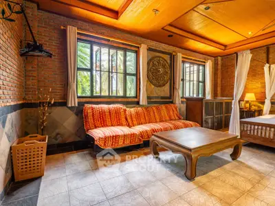Charming living room with rustic brick walls and cozy seating area, featuring large windows and warm lighting.