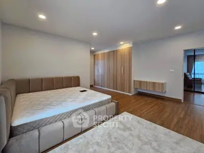 Spacious modern bedroom with elegant wooden flooring and built-in wardrobe
