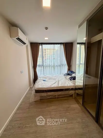 Modern bedroom with large windows and mirrored wardrobe in a stylish apartment.