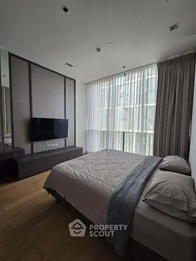 Modern bedroom with large window and stylish decor in a luxury apartment.