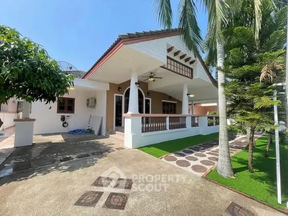 Charming single-story house with spacious porch and lush greenery, perfect for serene living.