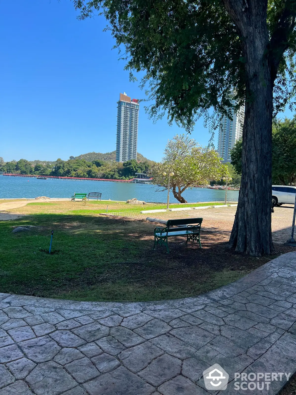 Serene lakeside park with a view of towering residential skyscrapers, offering a tranquil urban living experience close to nature.