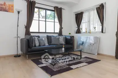 Stylish living room with modern decor, featuring a black sofa, coffee table, and large windows for natural light.