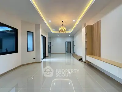 Spacious modern living room with elegant ceiling lighting and sleek tile flooring.