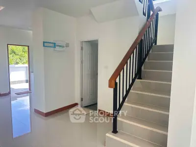 Bright modern interior with staircase and open doorway leading to balcony.