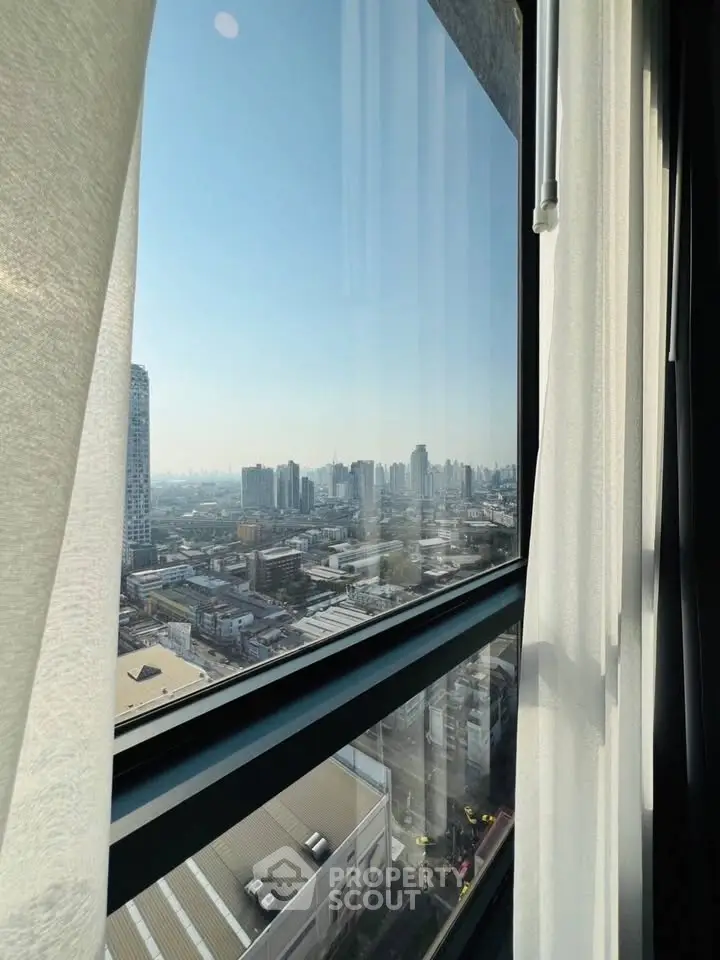 Stunning cityscape view from high-rise apartment window with sheer curtains