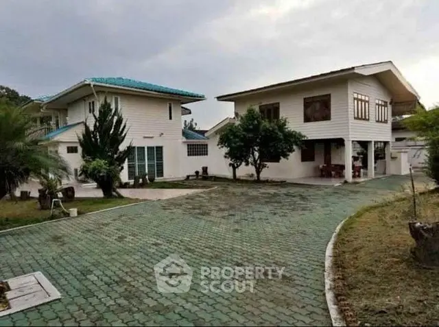 Spacious two-story house with large driveway and lush greenery, perfect for family living.