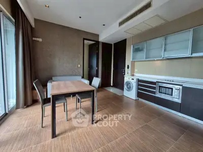 Modern open-layout kitchen with dining area and washing machine in stylish apartment.