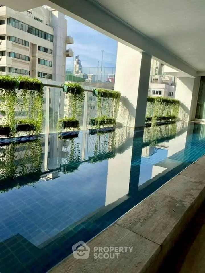 Luxurious rooftop pool with stunning city views and lush greenery, perfect for relaxation and leisure.
