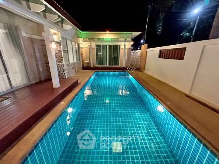 Luxurious night view of a private pool beside a modern house with elegant lighting.
