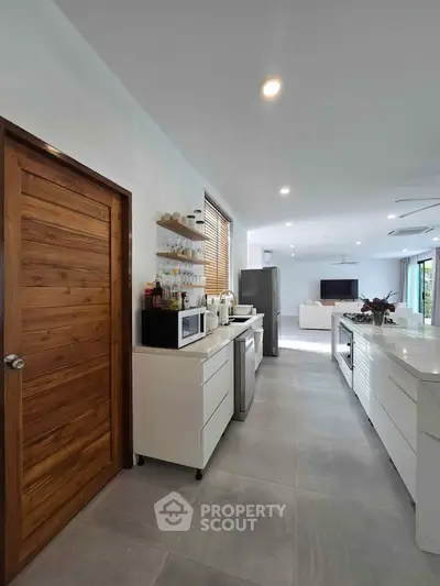 Modern open-layout kitchen with sleek white cabinets and stainless steel appliances
