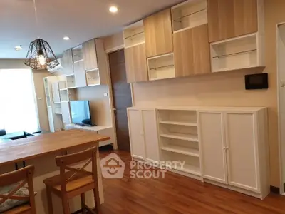 Modern living room with stylish wooden cabinets and open shelving, featuring warm lighting and hardwood floors.