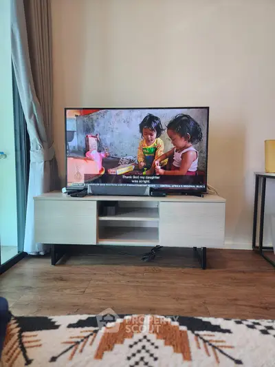 Modern living room with stylish TV stand and large flat-screen TV, showcasing cozy interior design.