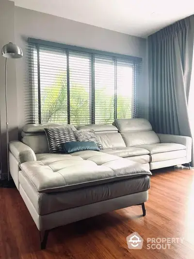 Modern living room with stylish leather sofa and large window with blinds