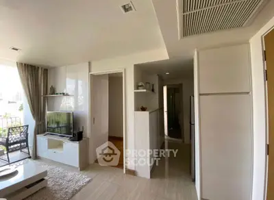 Modern living room with open layout and balcony view, featuring sleek furniture and natural light.