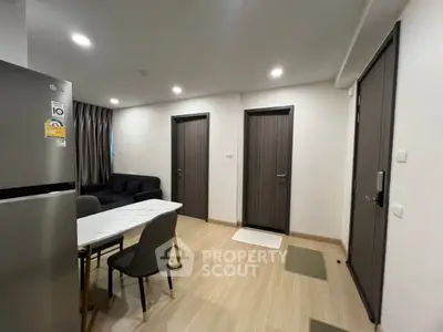 Modern apartment interior with dining area and living room, featuring sleek furniture and wooden flooring.