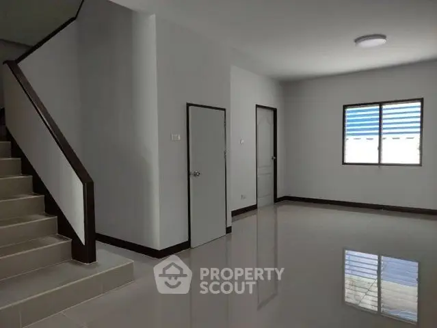 Spacious modern interior with sleek staircase and natural light.