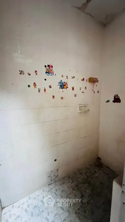Small bathroom with tiled walls and floor, featuring playful cartoon stickers for a fun touch.