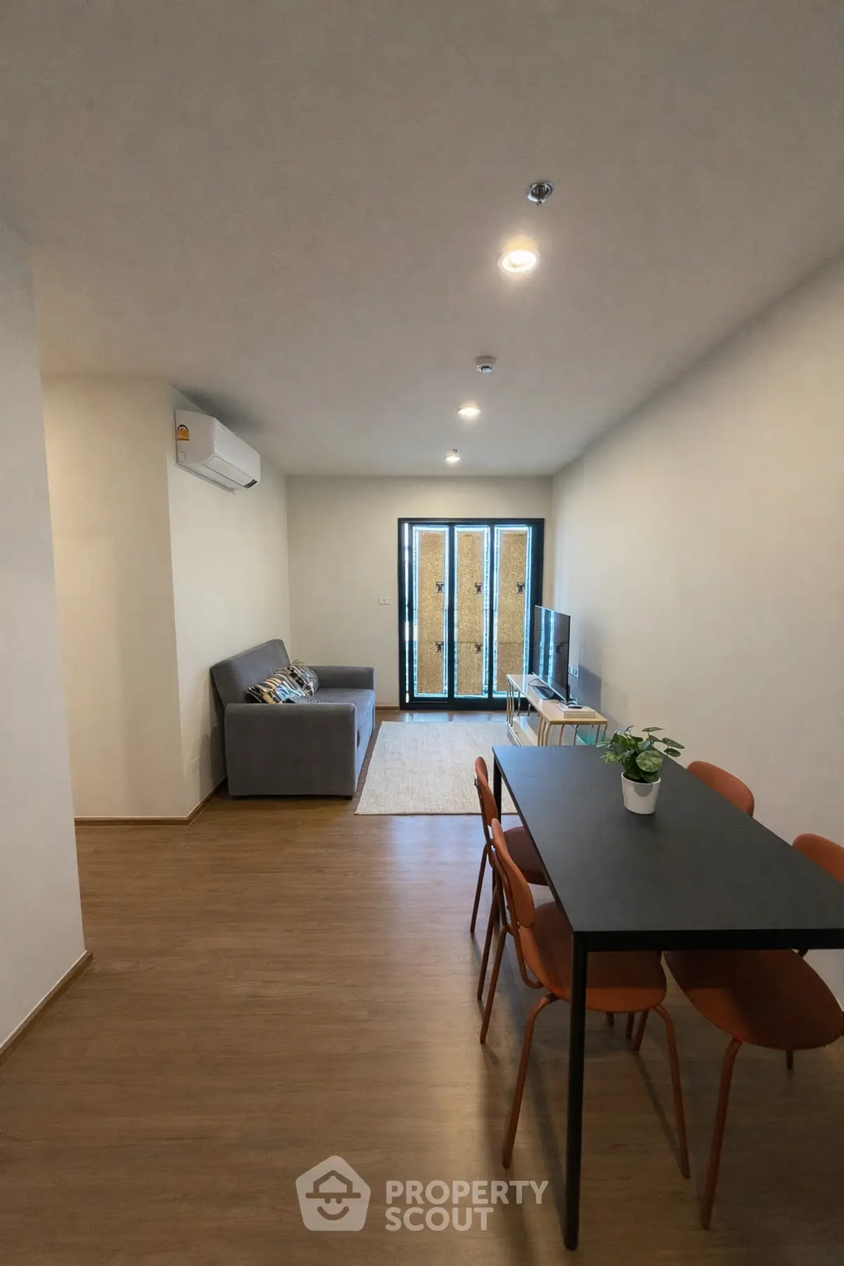 Modern living room with sleek furniture and wooden flooring, featuring a cozy sofa and dining area.