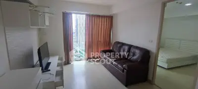 Modern living room with leather sofa and TV, adjacent to a bedroom with natural light.