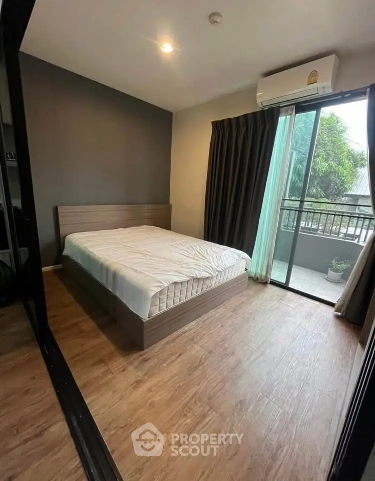Modern bedroom with wooden flooring and balcony access in a stylish apartment.