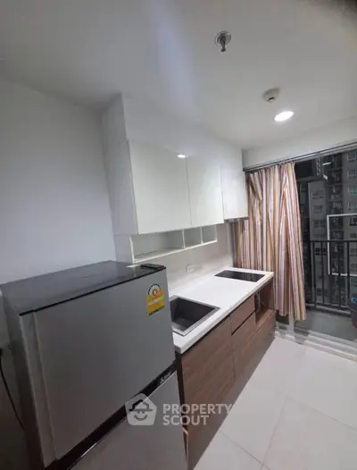 Modern kitchen with sleek cabinetry and balcony view in urban apartment.