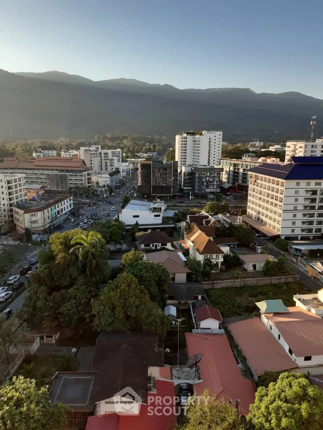 Stunning cityscape view with mountains, showcasing urban and residential buildings at sunrise.