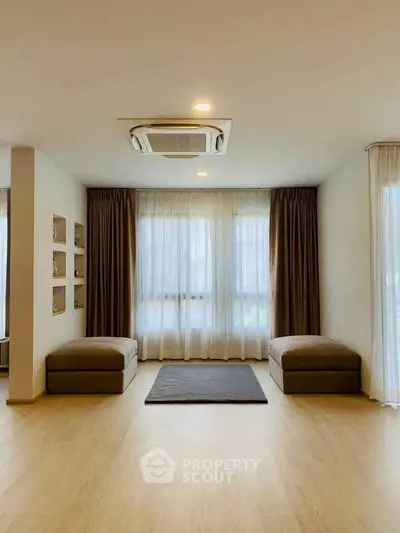 Spacious minimalist living room with large windows and elegant curtains