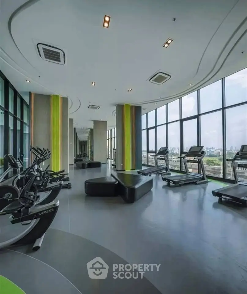 Modern gym with panoramic city views and state-of-the-art equipment in luxury building.