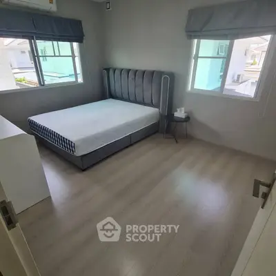 Spacious bedroom with modern design and ample natural light from two windows.